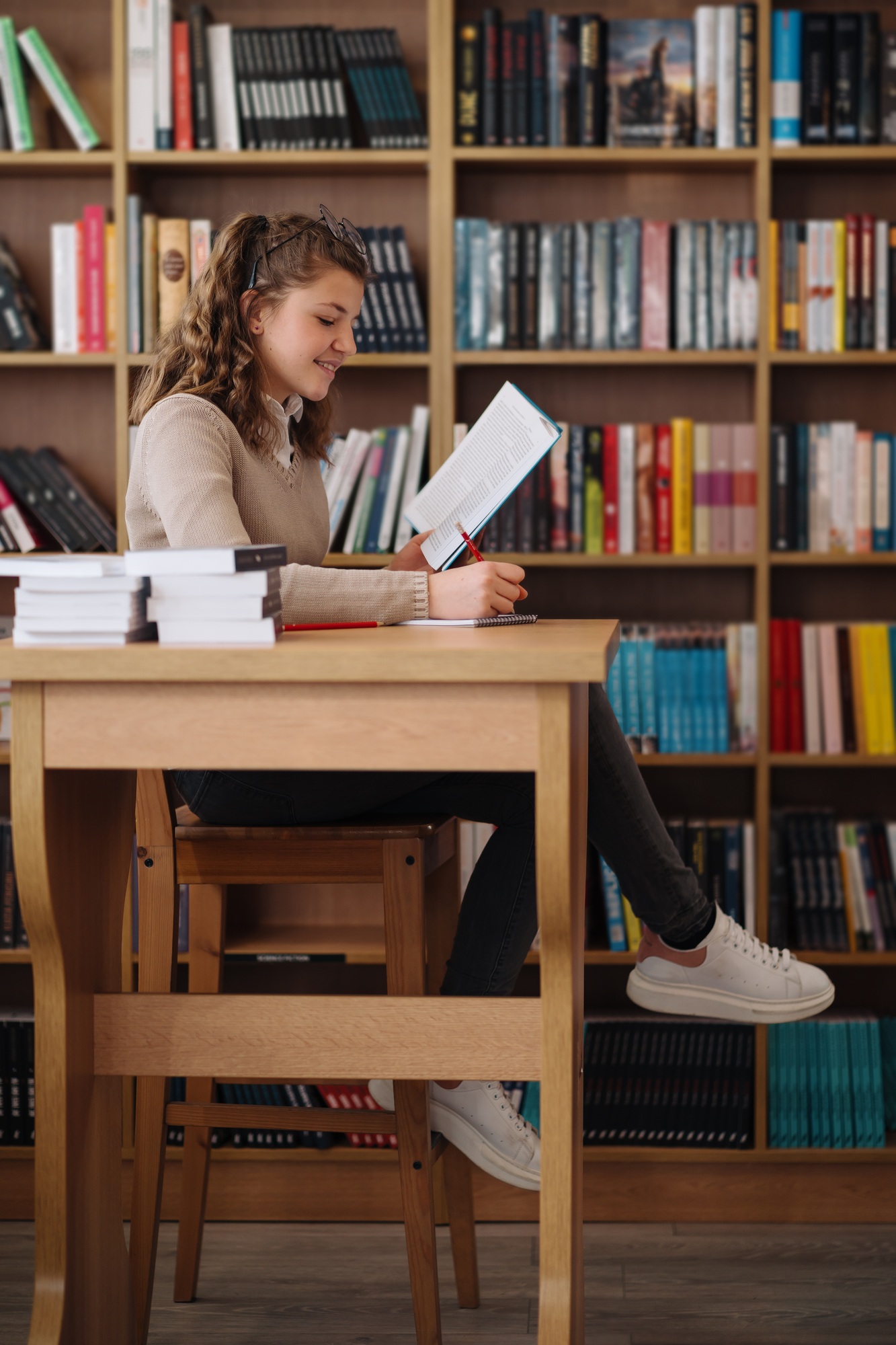 Engaged in Learning, young woman reading a book and taking notes in a library setting